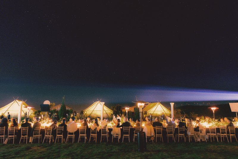 An outdoor wedding reception beneath the evening sky